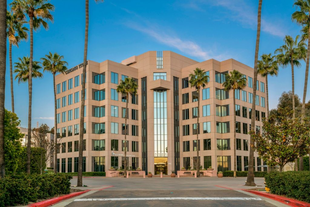 Modern office building surrounded by palm trees.